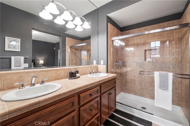 bathroom with vanity, tasteful backsplash, a chandelier, and walk in shower