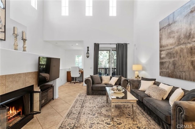 tiled living room featuring a towering ceiling and a tile fireplace