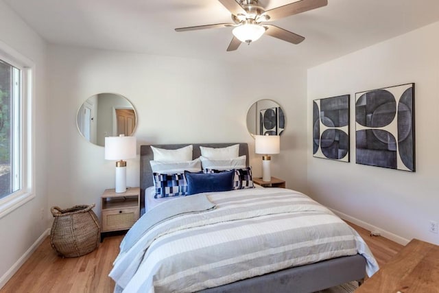 bedroom featuring ceiling fan, light wood-type flooring, and multiple windows