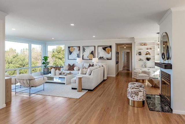 living room featuring a premium fireplace, crown molding, and light hardwood / wood-style floors