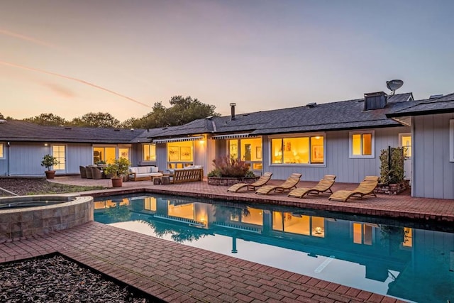 pool at dusk with an in ground hot tub and a patio