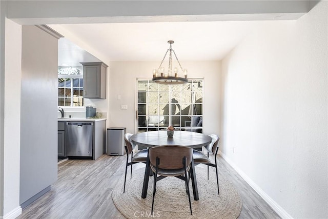 dining space featuring light hardwood / wood-style floors, sink, and a notable chandelier