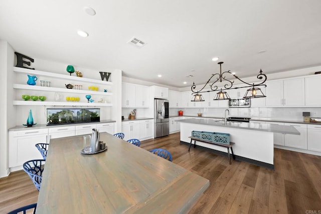 kitchen featuring an island with sink, appliances with stainless steel finishes, dark wood-type flooring, and white cabinets