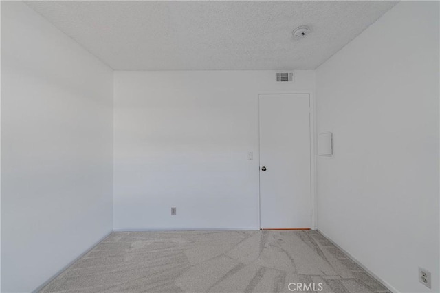 carpeted empty room with a textured ceiling