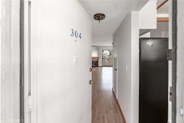 hallway with a textured ceiling and light hardwood / wood-style floors