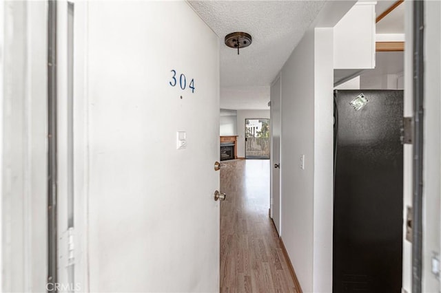 corridor with wood finished floors and a textured ceiling