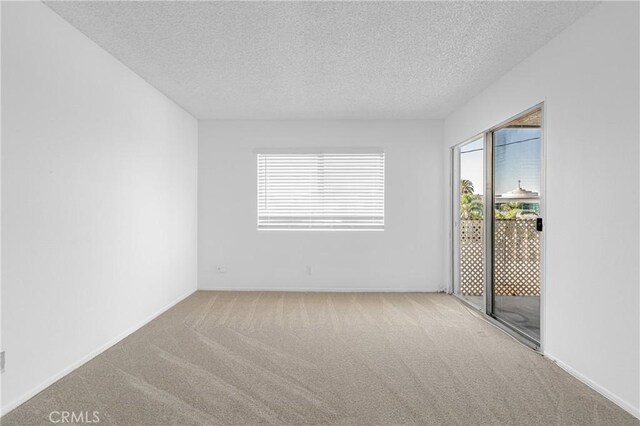 unfurnished room with carpet, a textured ceiling, and baseboards