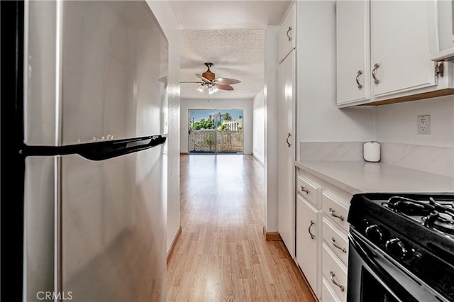 kitchen with ceiling fan, stainless steel refrigerator, black range with gas cooktop, a textured ceiling, and white cabinets