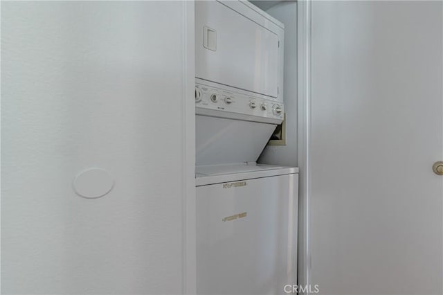 clothes washing area with stacked washer / dryer and laundry area