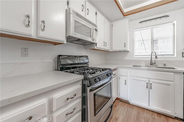 kitchen with sink, light hardwood / wood-style flooring, white cabinets, and stainless steel gas range oven