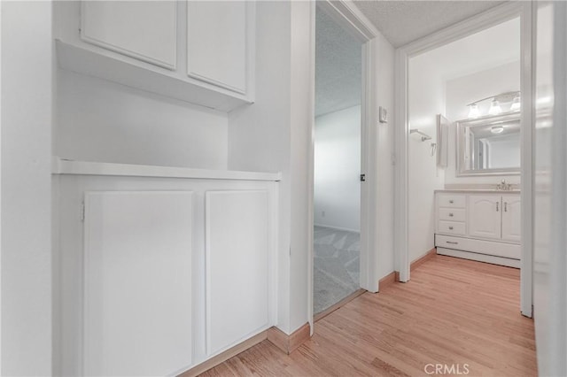 interior space with a sink, baseboards, and light wood finished floors