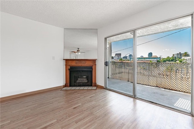 unfurnished living room with a fireplace with flush hearth, ceiling fan, a textured ceiling, and wood finished floors