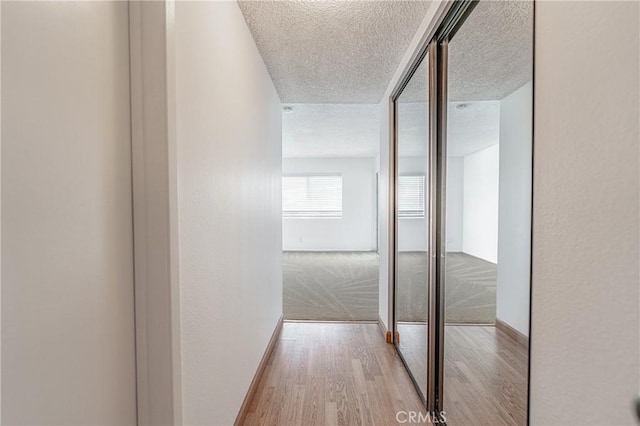 corridor featuring a textured ceiling and light wood-type flooring