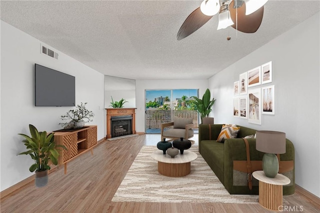 955 E 3rd St Unit 304, Long Beach, CA 90802 - living area featuring wood finished floors, a fireplace, a textured ceiling, a ceiling fan, and baseboards