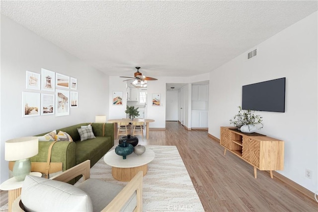 955 E 3rd St Unit 304, Long Beach, CA 90802 - living room featuring ceiling fan, light wood-style flooring, a textured ceiling, and baseboards