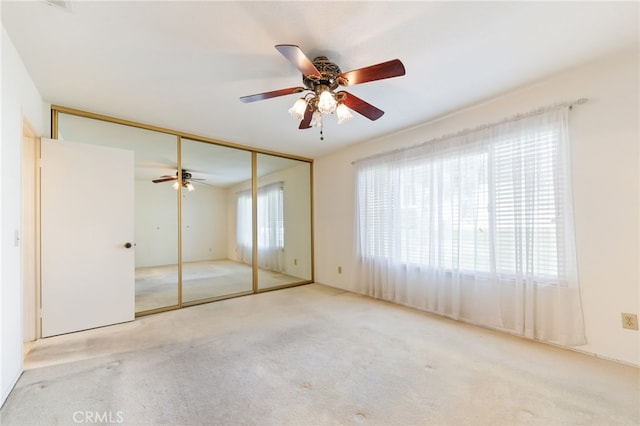 unfurnished bedroom featuring ceiling fan, a closet, and light carpet