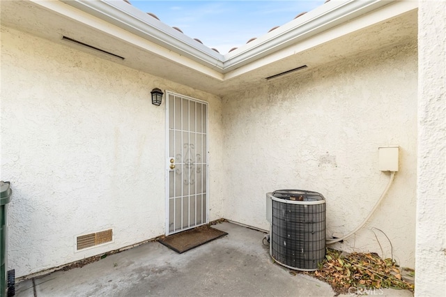 view of exterior entry featuring a patio area and central air condition unit