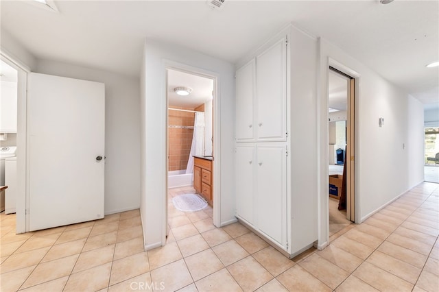 corridor with light tile patterned floors and washer / clothes dryer