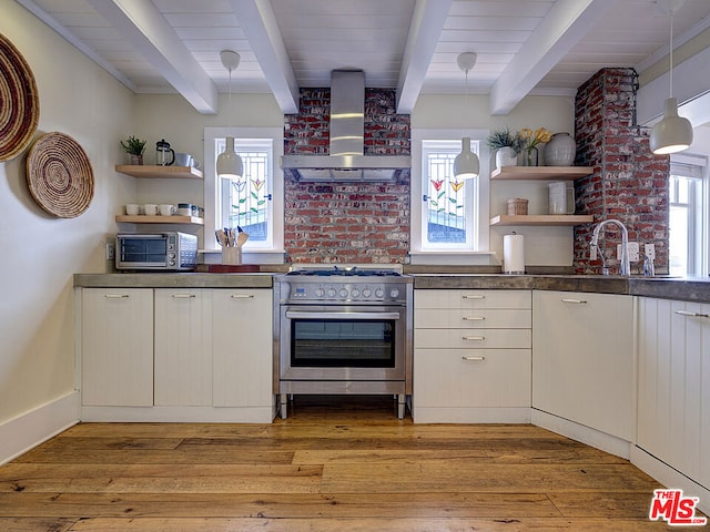 kitchen featuring high end stainless steel range, pendant lighting, white cabinetry, wall chimney range hood, and beam ceiling