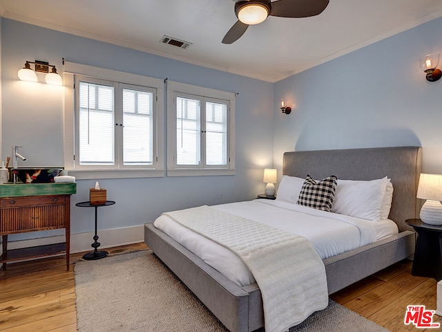 bedroom featuring ceiling fan, crown molding, and light hardwood / wood-style flooring