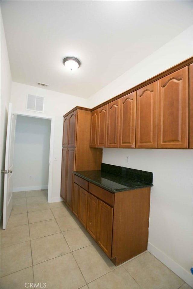 kitchen with light tile patterned floors and dark stone counters