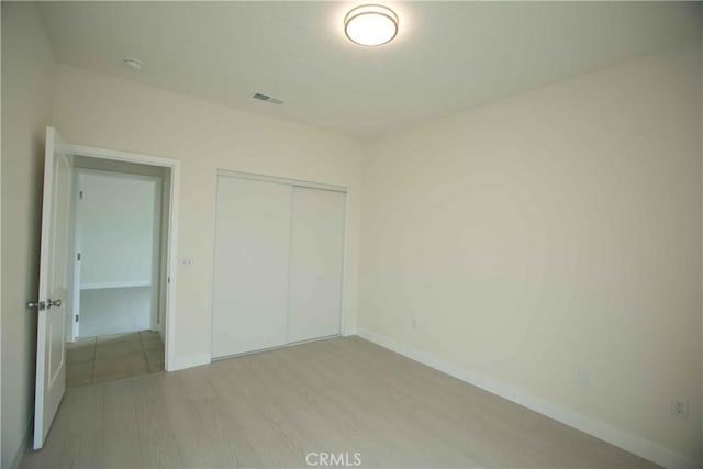 unfurnished bedroom with a closet and light hardwood / wood-style flooring