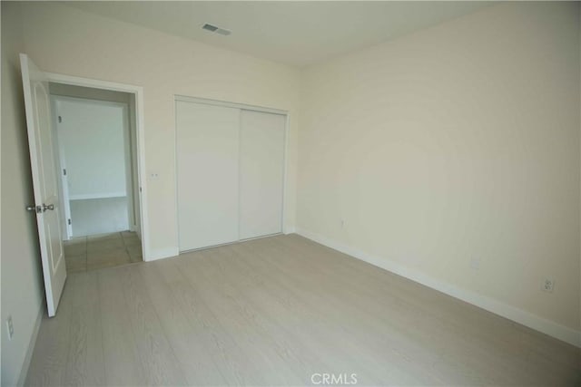 unfurnished bedroom with a closet and light hardwood / wood-style floors