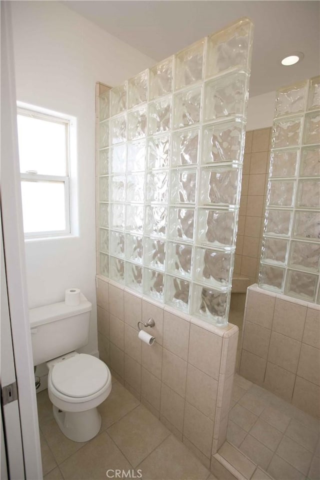 bathroom with a shower, toilet, and tile patterned flooring