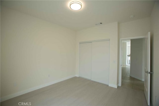 unfurnished bedroom with light wood-type flooring and a closet