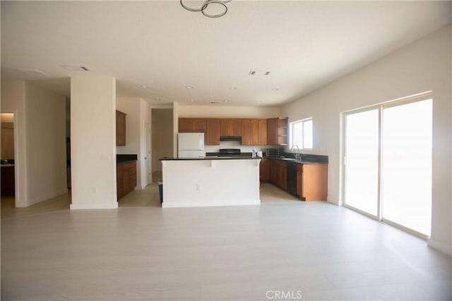 kitchen with black dishwasher, sink, white fridge, and a kitchen island