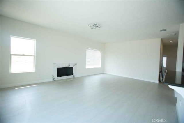 unfurnished living room with a high end fireplace and wood-type flooring