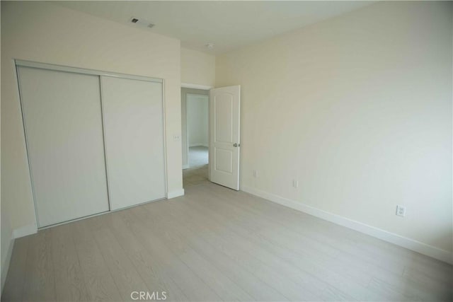 unfurnished bedroom with a closet and light hardwood / wood-style floors