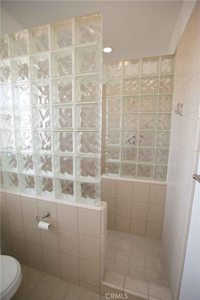 bathroom with toilet, a shower, and tile patterned floors