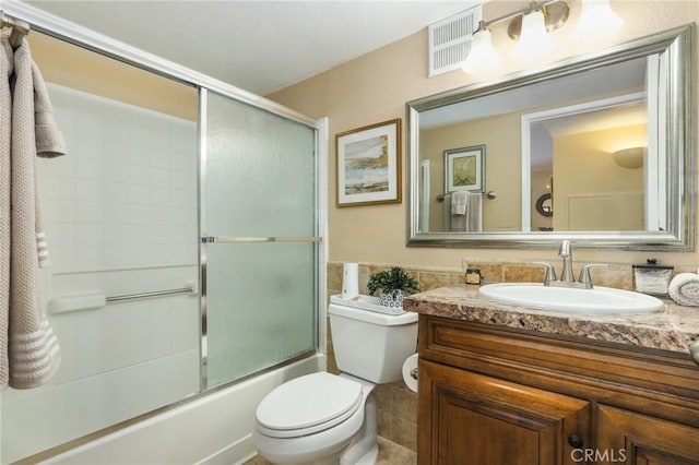 full bathroom with toilet, vanity, and enclosed tub / shower combo