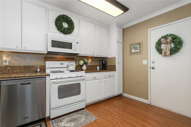 kitchen with white cabinetry, white appliances, dark stone counters, crown molding, and light hardwood / wood-style flooring