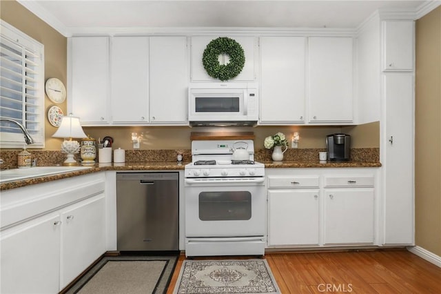 kitchen with sink, dark stone countertops, white cabinets, and white appliances