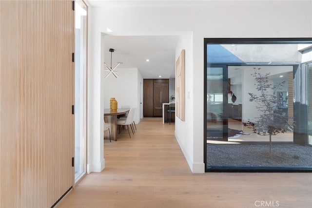 corridor featuring a notable chandelier and light wood-type flooring