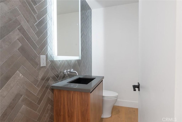 bathroom featuring toilet, vanity, and tasteful backsplash