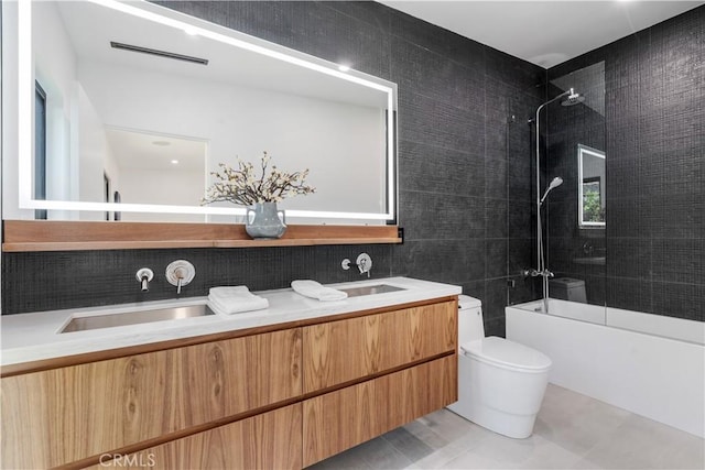 full bathroom featuring toilet, tiled shower / bath, tile walls, vanity, and tile patterned floors