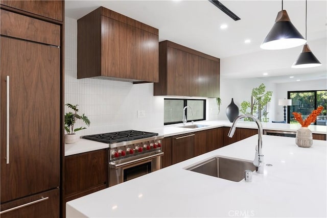 kitchen with decorative backsplash, pendant lighting, high quality appliances, and sink