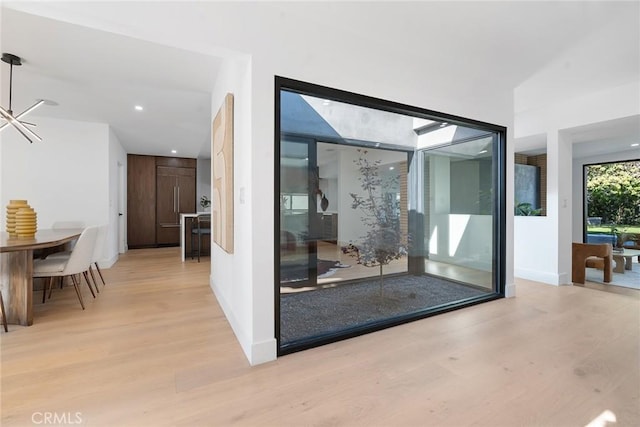 doorway featuring a skylight, an inviting chandelier, and light hardwood / wood-style flooring