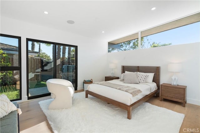 bedroom featuring light hardwood / wood-style floors, access to exterior, and multiple windows