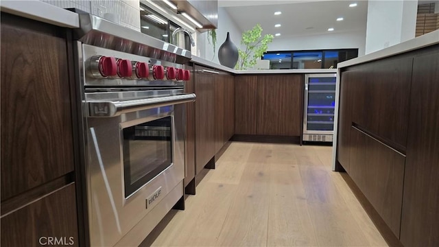 kitchen with designer stove, dark brown cabinets, and light hardwood / wood-style flooring