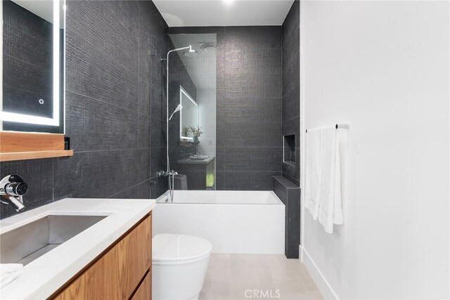 full bathroom featuring tiled shower / bath combo, vanity, and toilet