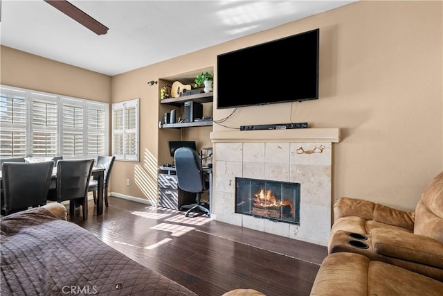 living room featuring ceiling fan, dark wood-type flooring, and a tile fireplace