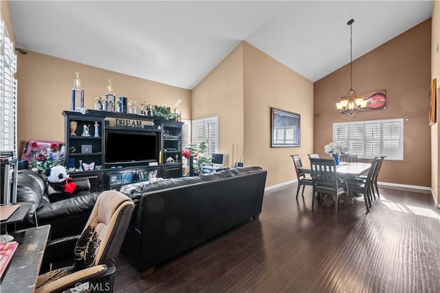 living room featuring lofted ceiling, dark wood-type flooring, plenty of natural light, and an inviting chandelier