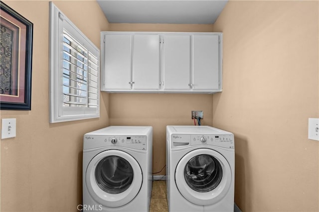 laundry area featuring washing machine and dryer, cabinets, and light tile patterned flooring