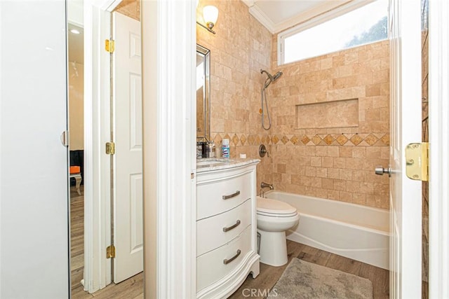 full bathroom with tiled shower / bath, wood-type flooring, vanity, toilet, and crown molding