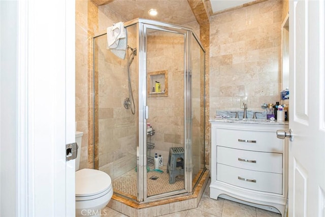 bathroom featuring a shower with shower door, tile walls, vanity, and tile patterned flooring