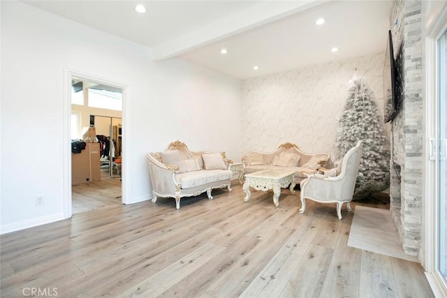 living area with beam ceiling and light wood-type flooring